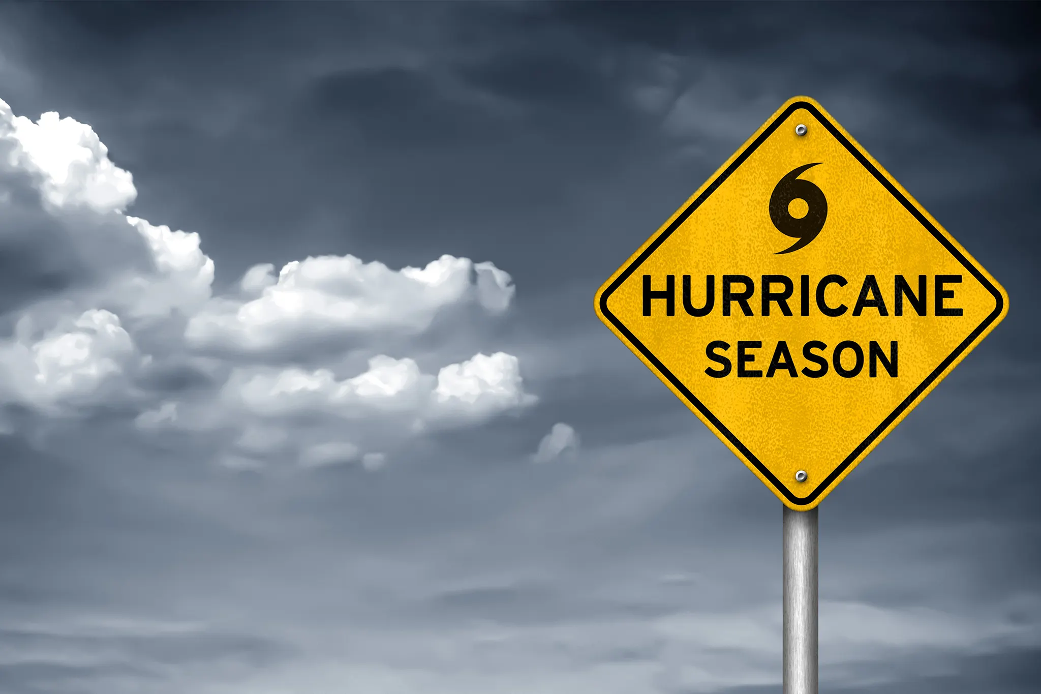 Yellow hurricane season road sign against a stormy sky background